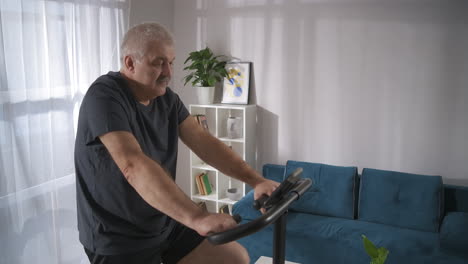 training-with-stationary-bicycle-in-home-middle-aged-man-is-keeping-fit-and-losing-weight-by-workout-fitness-and-health